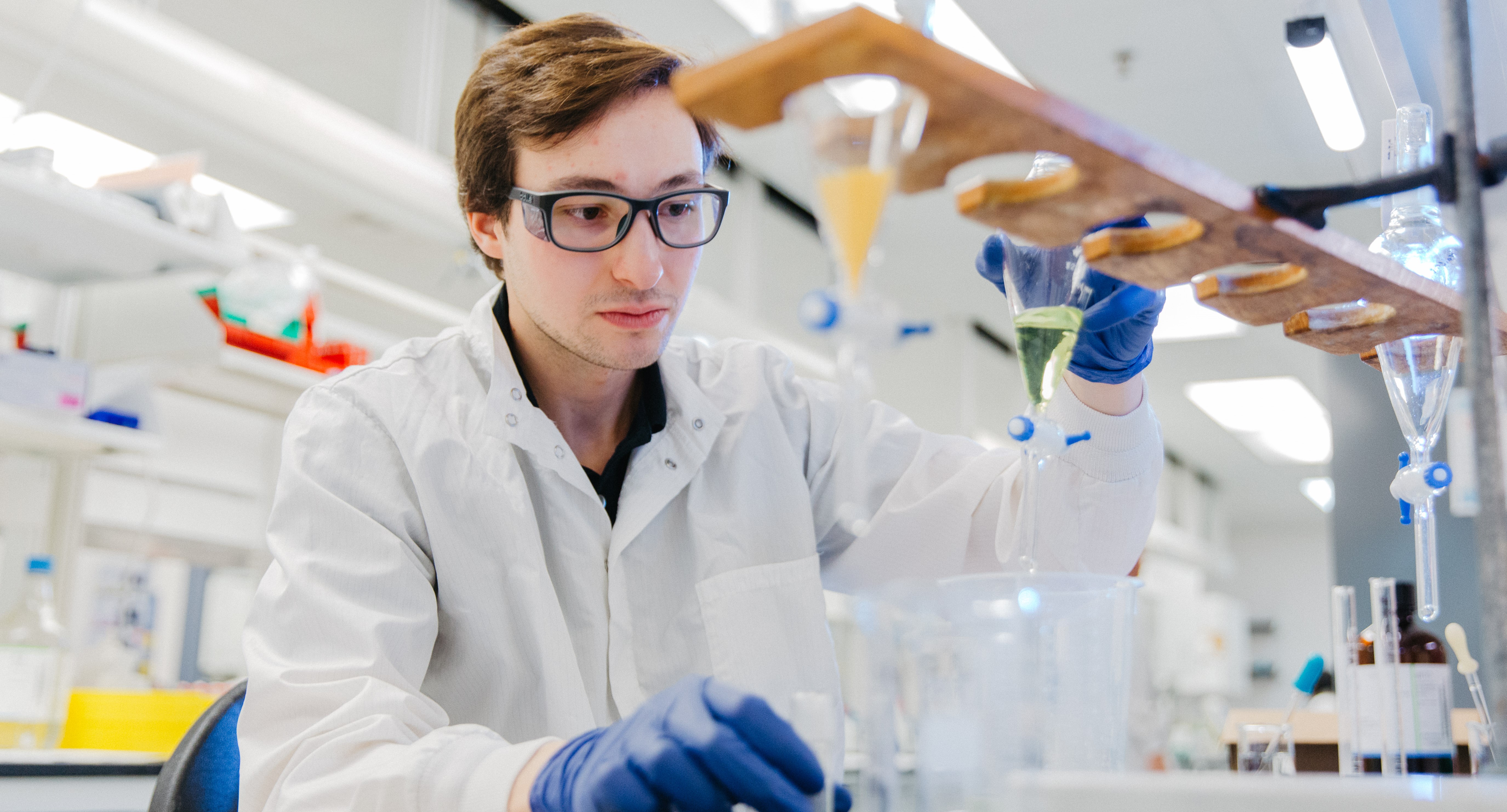 Person wearing lab coat and safety goggles works with lab equipment in sterile injectable facility in Rochester, Michigan